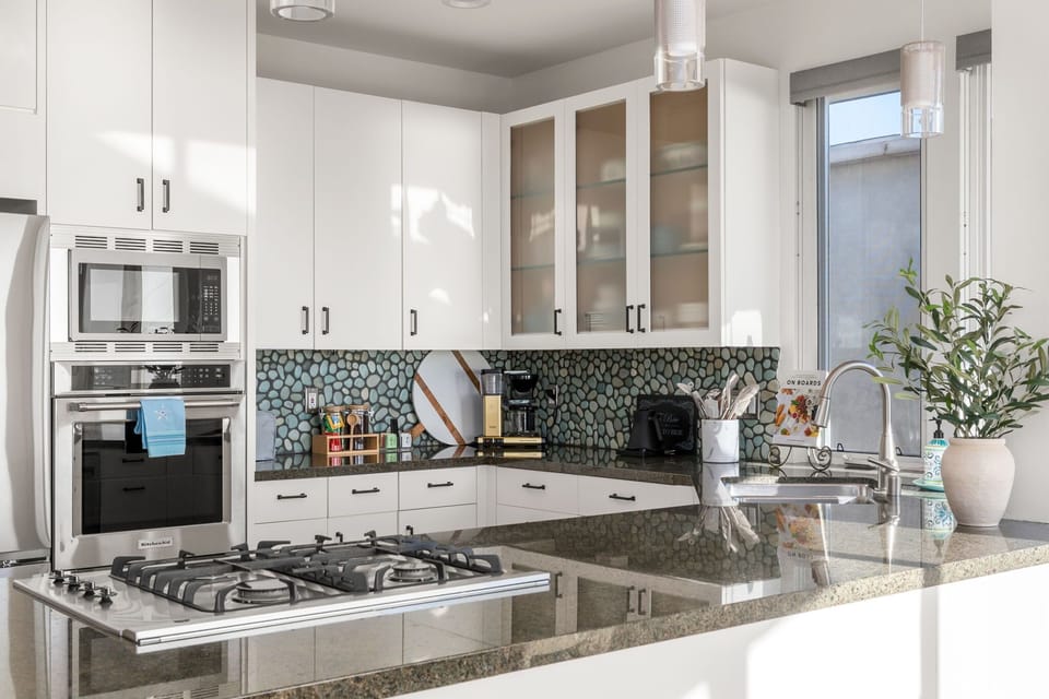 Thoughtfully designed kitchen with glass cabinetry, modern lighting, and a clean coastal aesthetic.