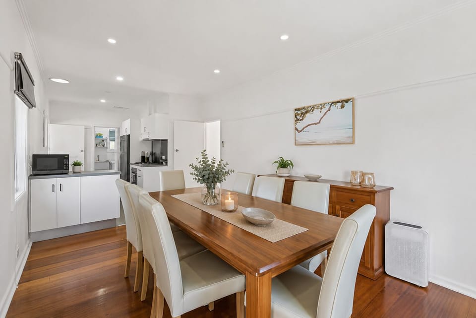 Bright dining for 8 with hardwood floors next to modern kitchen