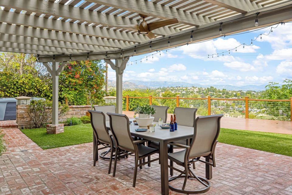 Al fresco dining under the pergola—string lights, ceiling fan, and wide-open valley views.