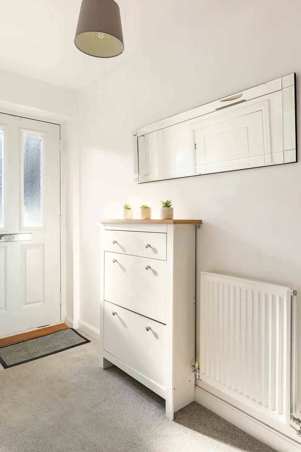 Step into a bright entryway with a sleek white door, chic mirror, and minimalist décor. Clean lines and soft tones set the stage for a warm, inviting stay.