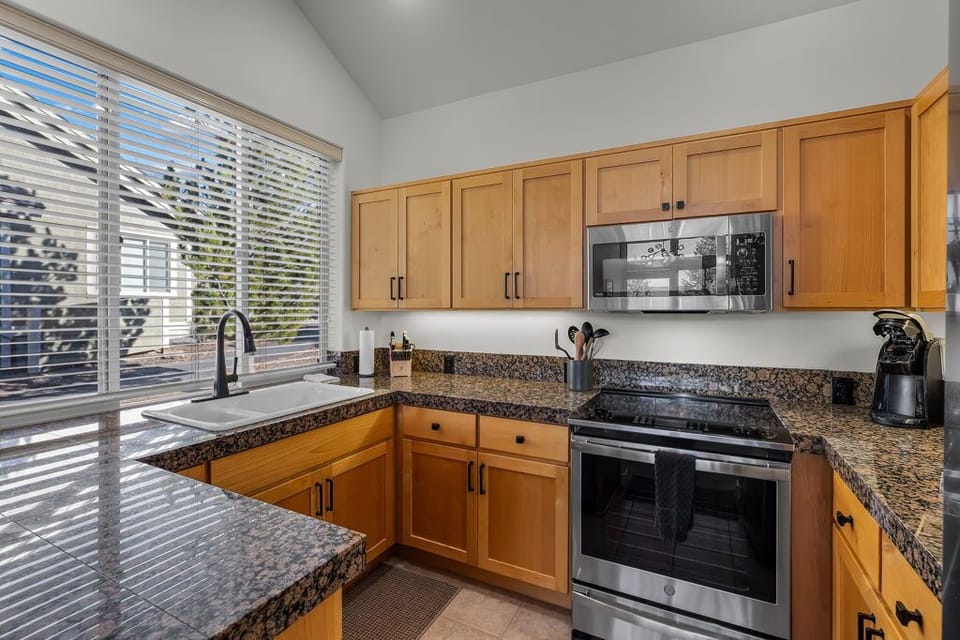 Your fully equipped kitchen features granite countertops, stainless appliances, and warm wood cabinetry—perfect for preparing meals while natural light streams through.