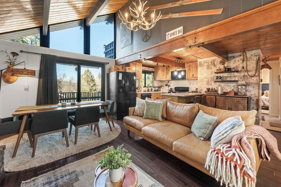 Living Room - Step inside to a bright great room with soaring vaulted plank ceilings, warm wood floors, and a cozy gas fireplace. The comfortable leather sofa and lounge seating create a welcoming space to unwind after a day exploring Big Bear. Large windows bring in mountain light and views while the Smart TV makes it easy to relax with your favorite shows.