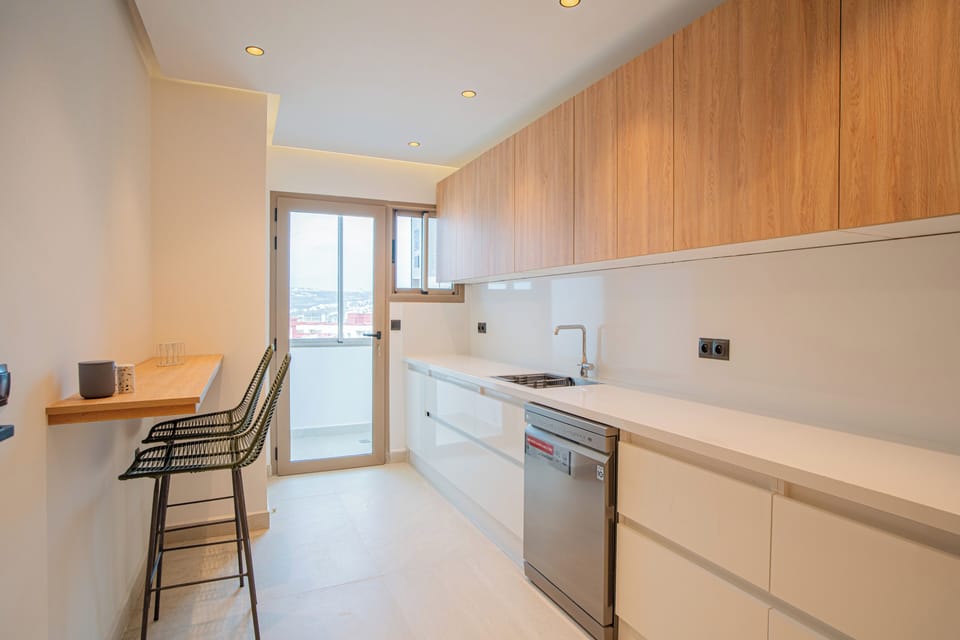 Kitchen with breakfast bar and two stool chairs, sink and LG dishwasher