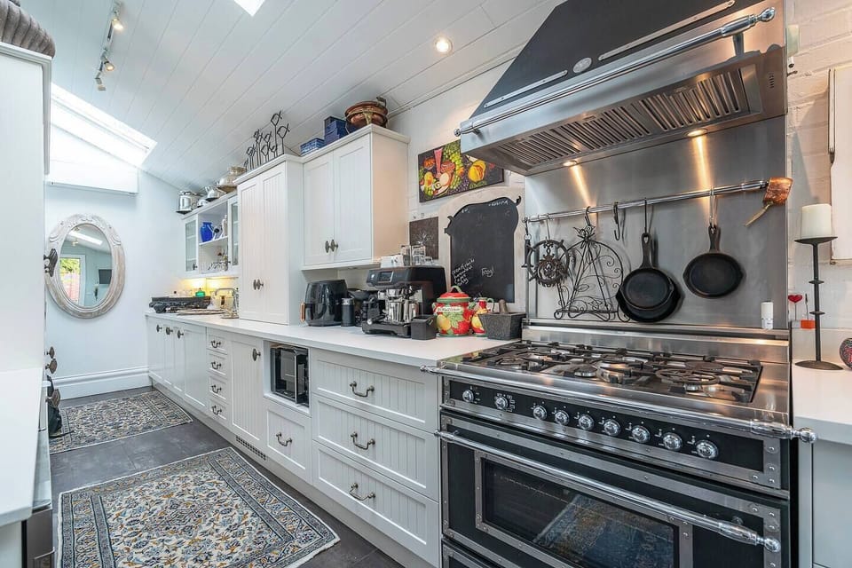 Cook with ease in the skylit kitchen, fully equipped with an oven, stovetop, microwave, dishwasher, fridge, and cooking basics for preparing meals at home.