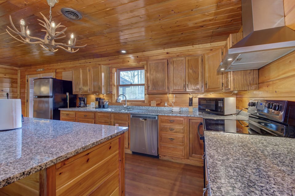 Your fully-equipped kitchen blends rustic charm with modern convenience, featuring granite countertops and warm wood cabinetry for memorable meal preparations.