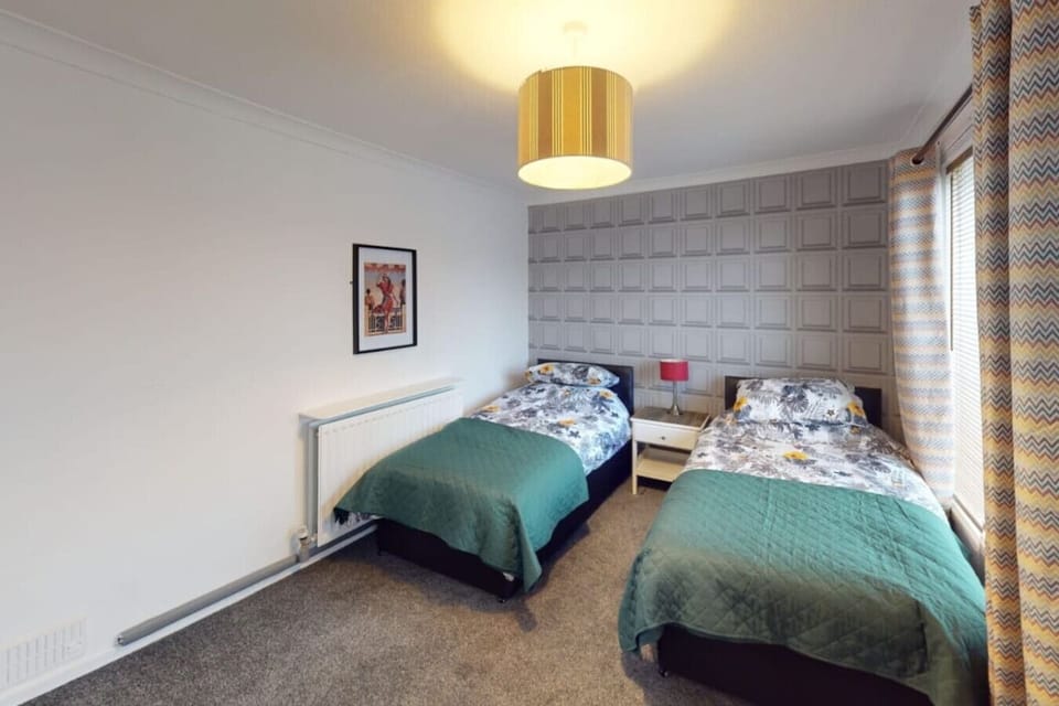 Both beds in the twin room are made up with teal quilts and bedside lamp in place, ready for guests to use on arrival.
