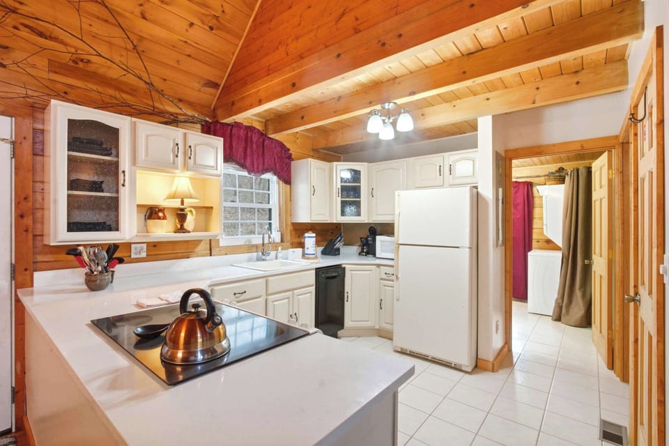 Detailed view of the kitchen featuring the latest appliances, including a dishwasher and stove, paired with warm wood-plank walls and ample counter space.