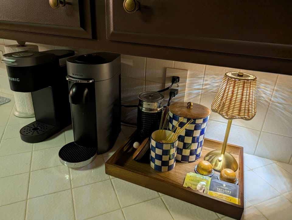 Cozy coffee corner with Keurig & Nespresso, tea & soft lighting.
