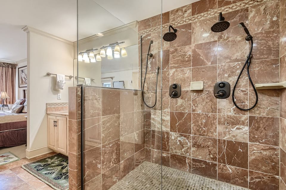 Step into your luxurious marble-tiled shower with dual rainfall heads and handheld sprays for the ultimate spa experience.