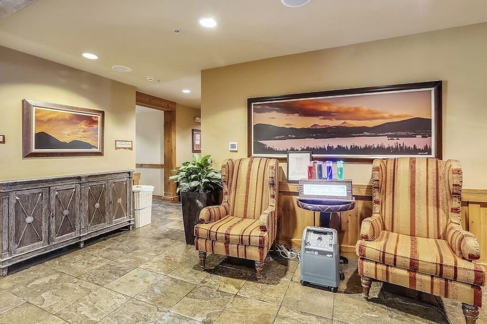Relax in comfortable striped armchairs while enjoying mountain landscape artwork and convenient refreshment stations in this welcoming lobby space.