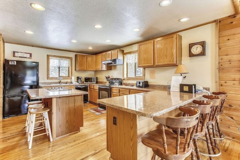 Your spacious kitchen features granite countertops, modern appliances, and rustic wood finishes - perfect for cooking meals together during your mountain retreat.