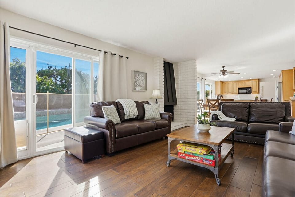 Bright living room w/ comfy sectional, large windows & sliding doors opening to the backyard