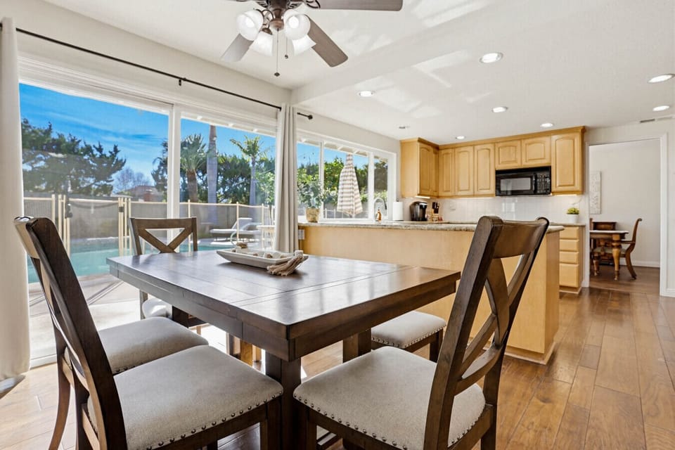 Open dining area w/ large table beside a bright kitchen, ideal for shared meals & conversation