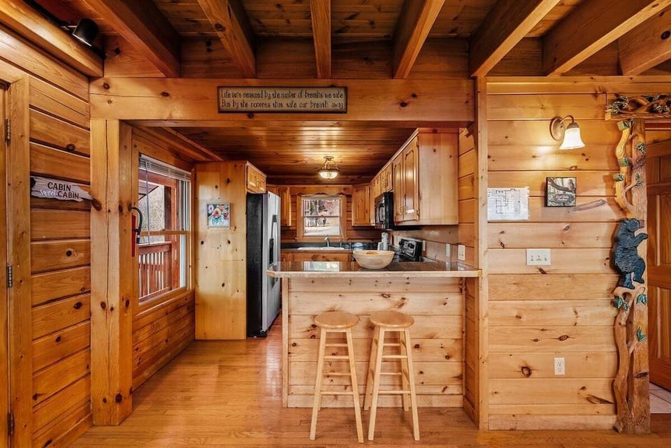 Rustic cabin kitchen with breakfast bar, wood cabinetry, open floor plan, and modern appliances in Sevierville TN rental.
