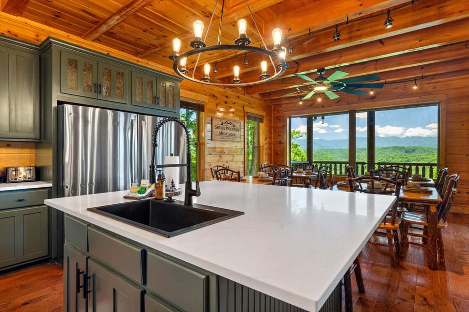 Full cabin kitchen with large island, stainless steel appliances, double dishwashers, microwave, oven, and green cabinetry.