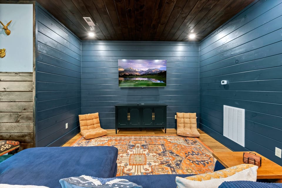 Lounge seating area with flat screen TV and mountain landscape art in the lower level game room at Blue Bird three-bedroom cabin in the Smoky Mountains, Tennessee