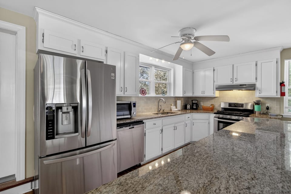 Bright, fully equipped kitchen with granite counters—perfect for cooking and serving up coastal feasts.
