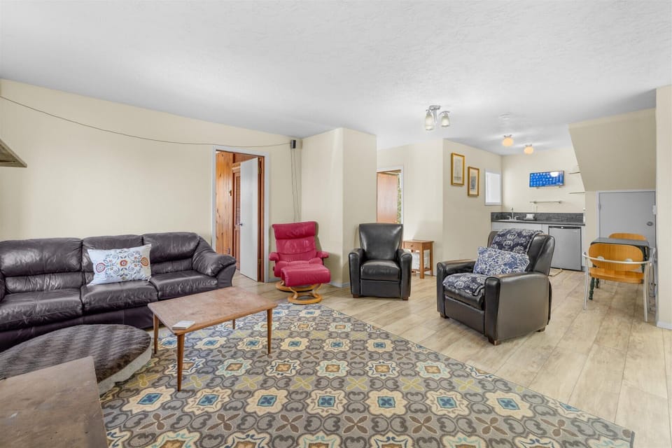 Relax in your spacious living room with plush leather seating and modern kitchen nearby for convenient meals.