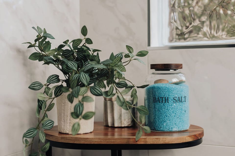 Unwind in your thoughtfully styled space with calming touches like fresh greenery and luxurious bath salts ready for your relaxation.