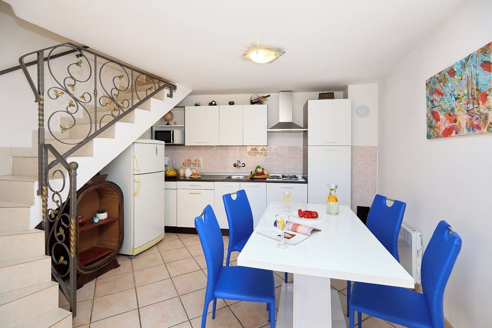 Gather for a meal in the bright, modern kitchen and dining area, where vibrant blue chairs add a playful touch to the space.