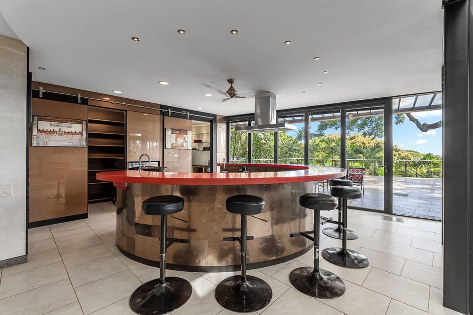 Modern kitchen features a stunning curved island with bar seating, perfect for morning coffee or evening cocktails while enjoying garden views.