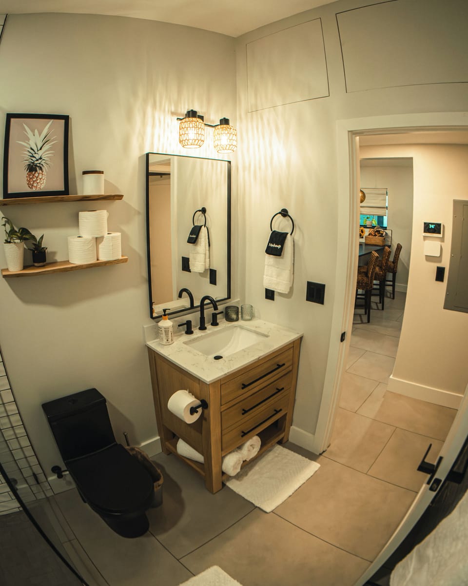 Modern bath with black fixtures, wood vanity & soft lighting