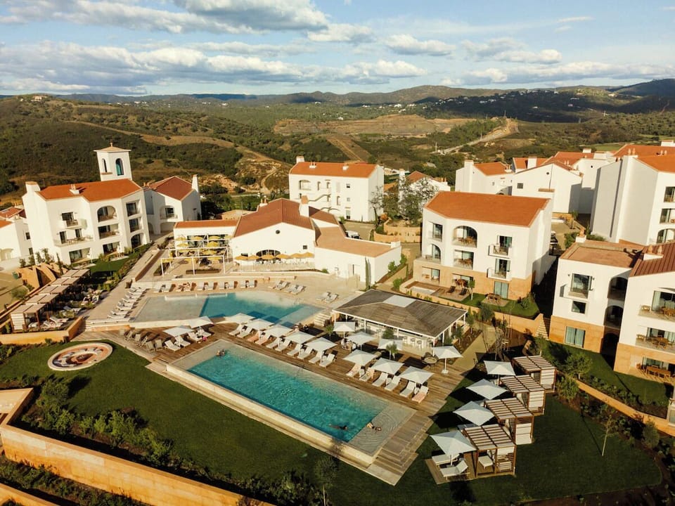 Arrive to a sunlit resort oasis with sweeping hillside views.