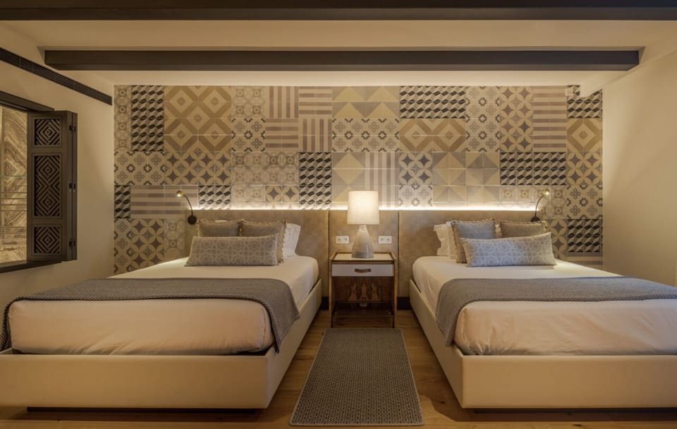 Drift off in twin beds beneath a warmly lit feature wall.