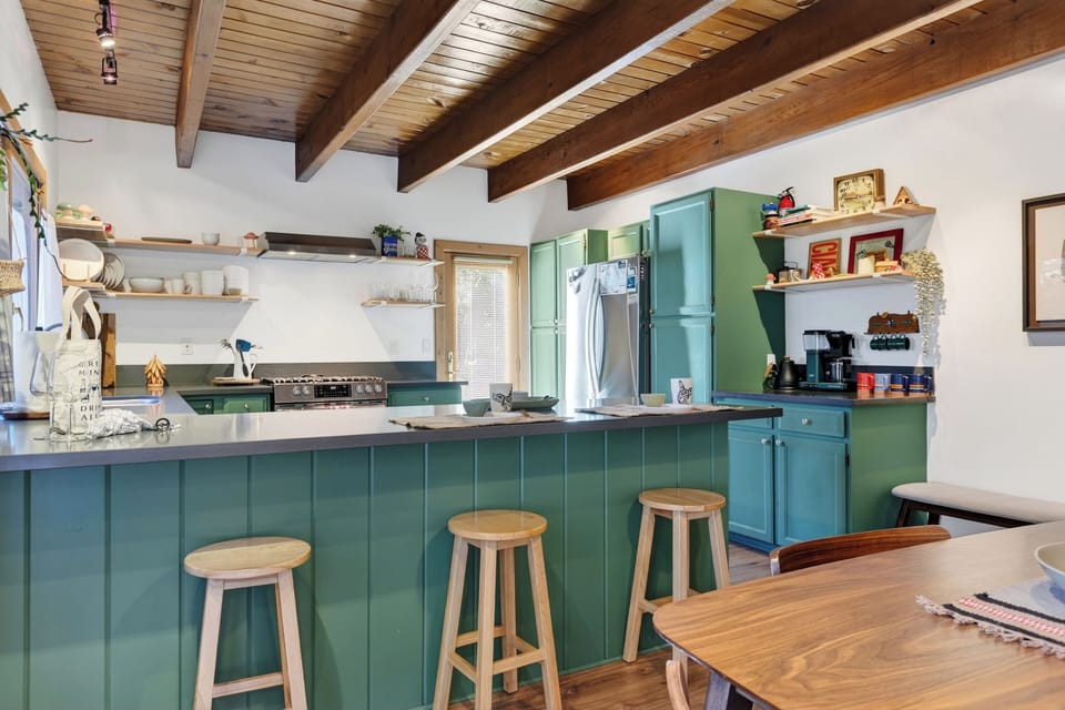 Gather in the open-concept kitchen with a big breakfast bar, vintage-chic green cabinetry, and warm wood-beam ceilings.