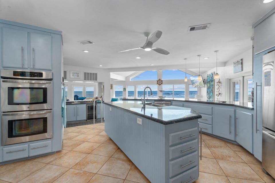 Fully equipped gourmet kitchen with large island, stainless steel appliances, and ocean views.