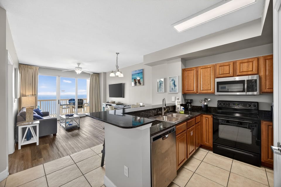 Your oceanfront kitchen flows seamlessly into the living space, where granite counters and modern appliances meet stunning sea views through floor-to-ceiling windows.