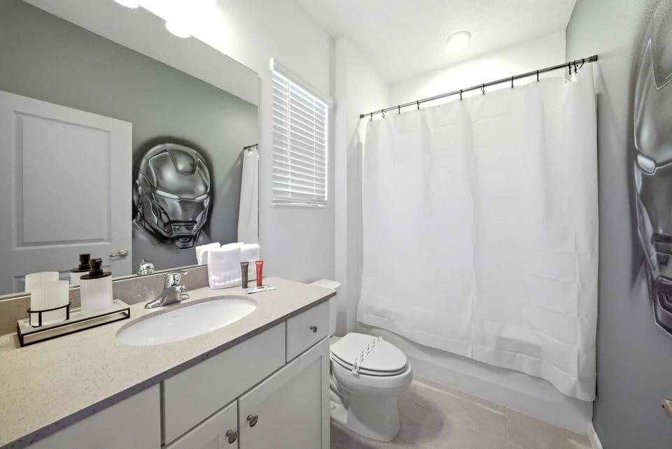 Relax in a bright, well-equipped bathroom featuring a spacious vanity for your essentials. The soft gray walls and natural light create a refreshing vibe, enhanced by a cozy white shower curtain for your comfort.