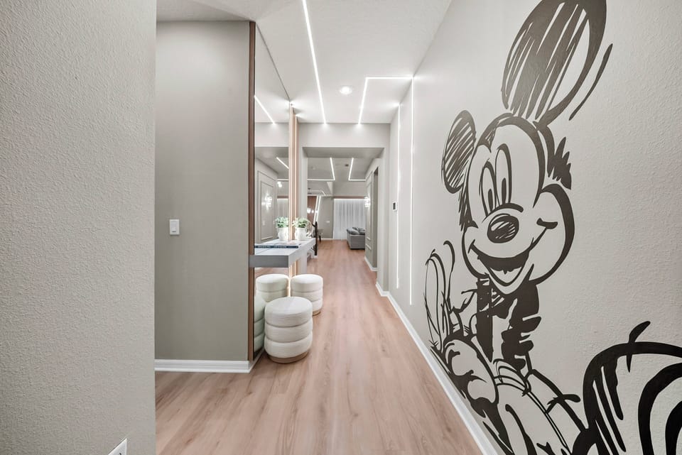 Experience a lively hallway featuring a charming Mickey Mouse mural that sets a cheerful mood for your stay. The sleek hardwood flooring and modern lighting create a bright, inviting pathway to your adventure.