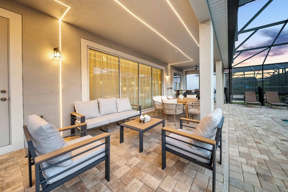 Step outside to enjoy the beautifully arranged patio with cozy gray seating and a stylish wooden coffee table. The warm lighting creates a welcoming atmosphere, perfect for relaxing evenings with loved ones.