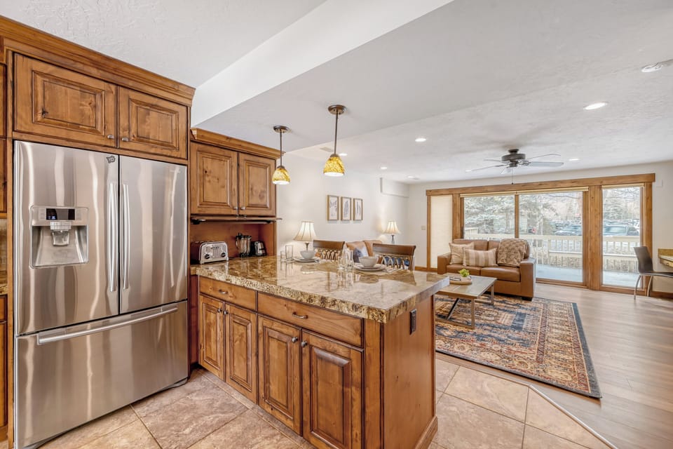 Your fully equipped kitchen features granite countertops, stainless appliances, and flows seamlessly into the cozy living area with mountain views.