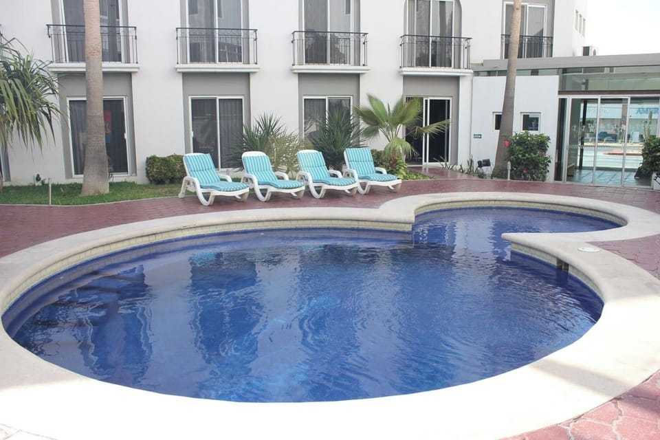 Unwind poolside in the sunshine with loungers and calm water.