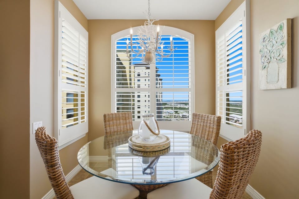 Beach Colony T PH1D- Enjoy meals in this sunny dining nook with stunning coastal views. The elegant chandelier and woven chairs create a relaxed, beachy atmosphere perfect for your morning coffee or evening gatherings.