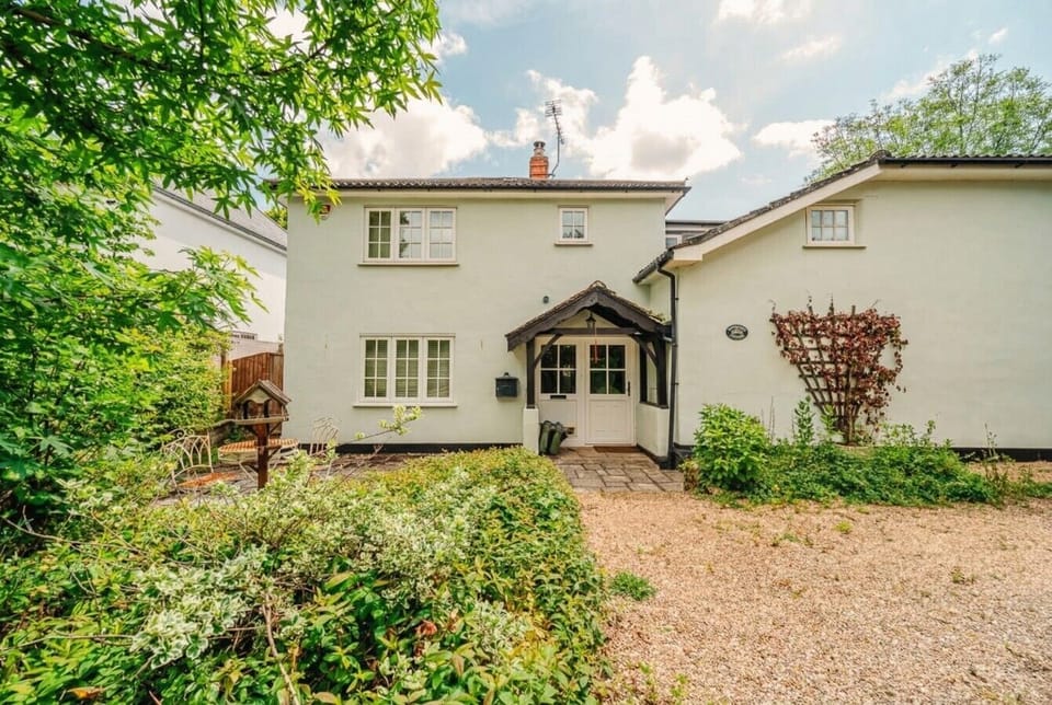 A classic English cottage wrapped in greenery waits to welcome you home.