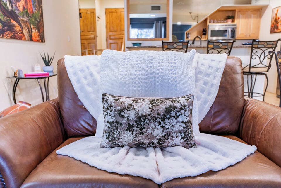 Sink into this inviting leather armchair with plush throws and pillows, perfectly positioned in your open-concept living space.