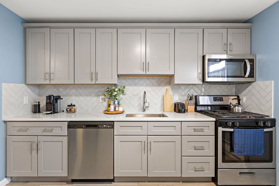 Kitchen: Stainless appliances, herringbone backsplash, and a gas range — a kitchen worth actually cooking in.