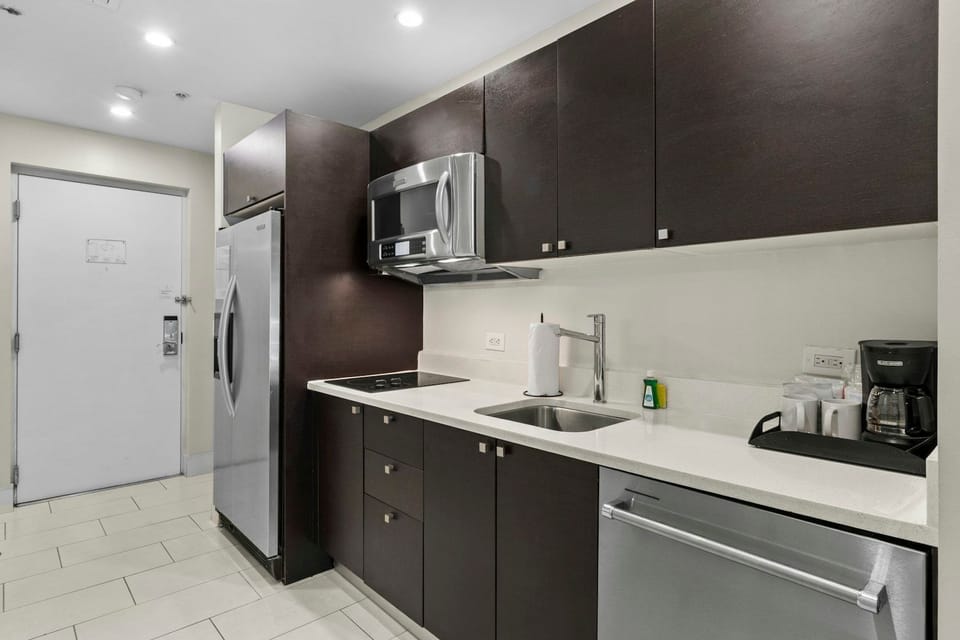 Contemporary kitchen featuring sleek cabinetry, full-size refrigerator, microwave, sink, and ample counter space.