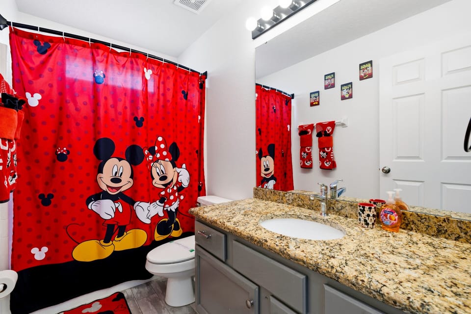 Bright bathroom with shower/tub combo and playful Disney touches.