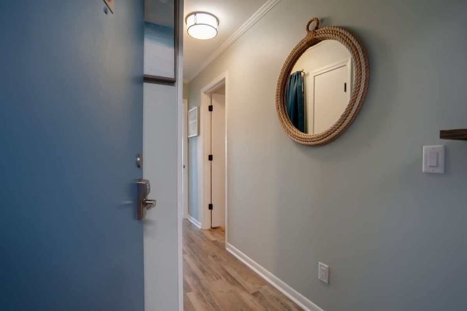 Step into your coastal-inspired entryway, where nautical charm meets modern comfort with rope-wrapped mirrors and soothing blue accents welcoming you home.