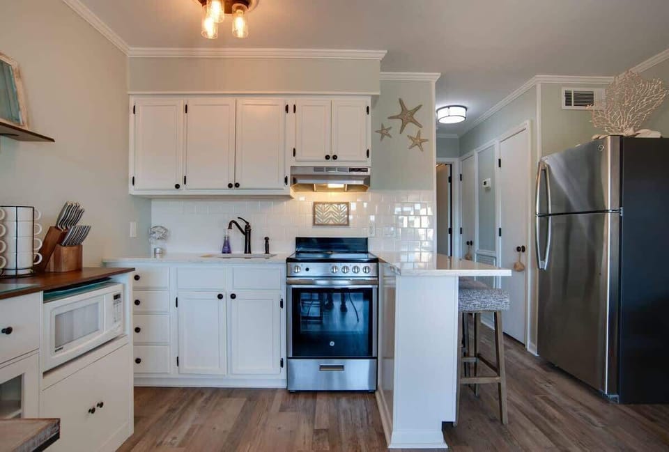Your coastal-inspired kitchen features crisp white cabinets, subway tile backsplash, and modern stainless appliances, perfect for preparing meals.