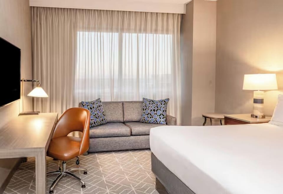 Unwind on crisp linens beside a cozy window-side sofa.