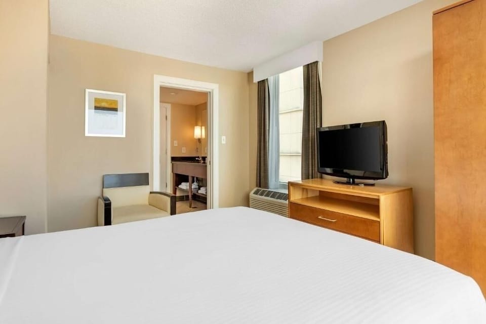 Recharge in a calm bedroom with TV and soft lighting.
