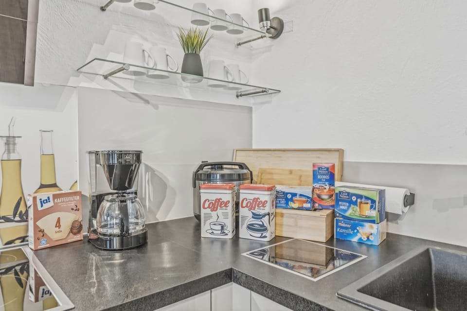 Küchenzeile mit Kaffeemaschine, Mixer, Kaffeepads und verschiedenen Frühstückszutaten.