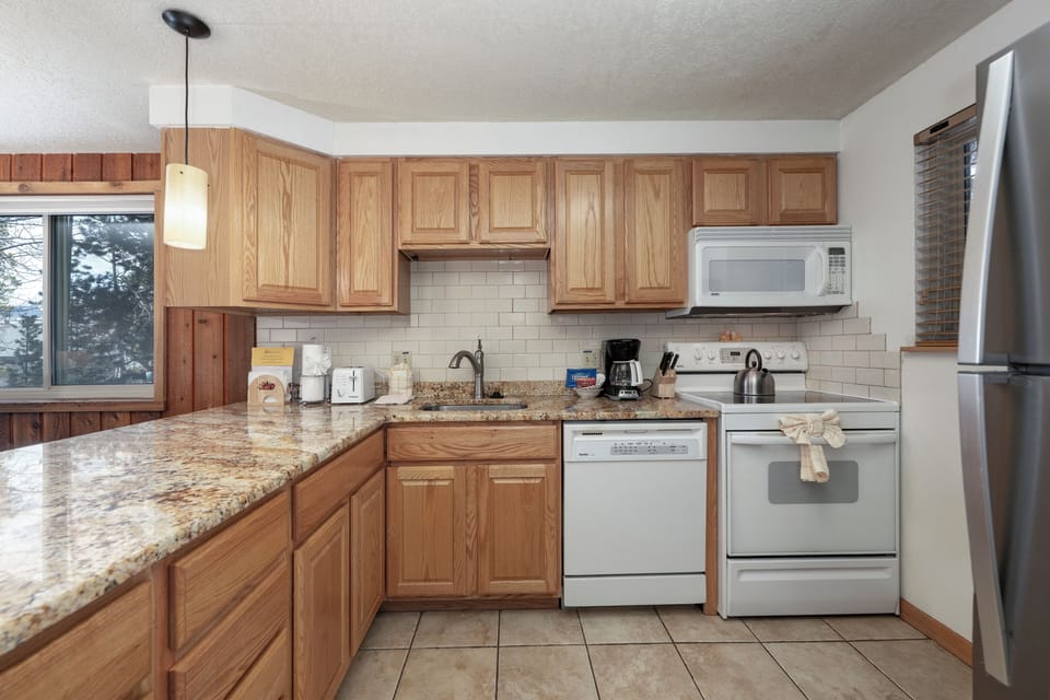 Your fully equipped kitchen features warm wood cabinets, granite countertops, and modern appliances for all your culinary needs.