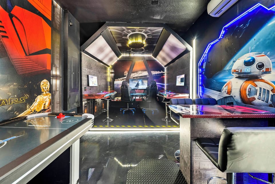 Discover an exciting game room filled with vibrant murals and glowing blue LED lights that create an immersive atmosphere. The sleek black surfaces and metallic accents add a futuristic touch for unforgettable evenings.