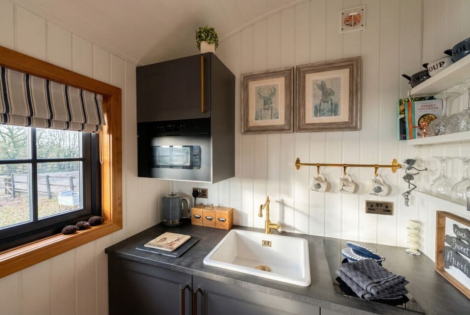 A fully equipped kitchen with brass fittings and a farmhouse sink to cook by.